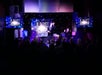 Performer on stage at a magic show with "Lioz Show" displayed on screens and backdrop, in front of an audience.