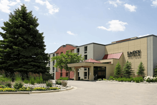 Exterior of the LivINN Hotel Minneapolis South / Burnsville with several trees out front of a bright sunny day.