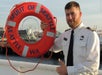 The Argosy Captain holding a life preserver that says "Spirit of Seattle" with the Ferris wheel in the background. Locks Cruise Seattle Washington.