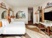 Two queen beds, TV, and a seating area in a guest room.