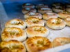 Rows of freshly baked bagels with golden brown tops are arranged on a parchment-lined baking tray.