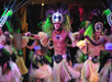 Male dancers in traditional Polynesian costumes perform a cultural dance, wearing feathered headdresses, grass skirts, and decorative accessories.