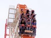 A group of people ride the Thunderbolt roller coaster, secured in their seats, as the coaster begins a steep drop.