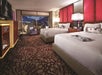 Two queen beds, work desk, and seating area inside a guest room.