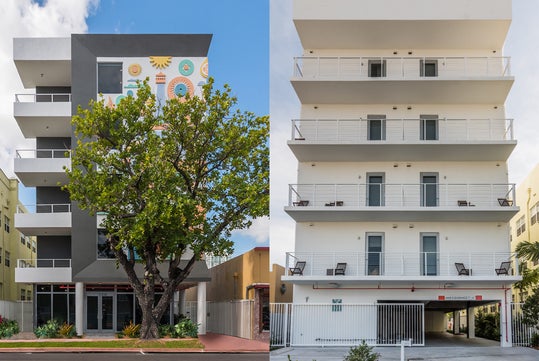 Side-by-side buildings; left has colorful mural and tree in front, right is plain with open ground level for parking.