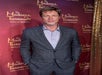 A wax figure of Brad Pitt, dressed in a stylish gray suit, standing confidently against a backdrop featuring the Madame Tussauds Hollywood logo at Madame Tussauds Hollywood.