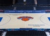 Empty basketball court at Madison Square Garden with New York Knicks logo at center, surrounded by seating and Chase branding.