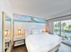A modern-style guest room with a king bed, private balcony, and a view of the ocean at Margaritaville Beach House Key West, FL.