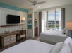 Guest room with two beds, wet bar and a balcony with view of the pool area.