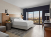 Rest easy in a king bed with natural light streaming through a large window.
