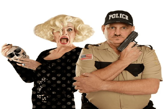 A person with blonde hair holds a skull and appears surprised, standing next to a person in a police uniform holding a gun against their shoulder.
