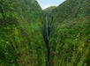 A waterfall flowing between two mountains into a crevice on the Maui Spectacular Helicopter Tour in Hawaii USA.