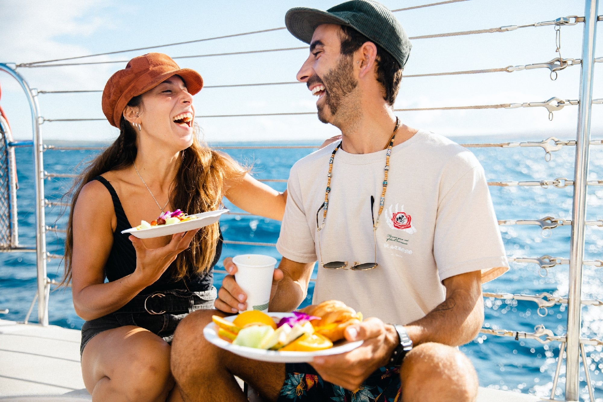 Couple laughing and enjoying fruit and pastries on a Maui sailing tour.