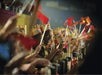 A group of people wearing paper crowns and waving small flags sit in an audience at a themed event, likely at Medieval Times.
