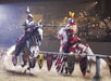 Two knights in armor joust on horseback in an arena, with lances breaking on impact and spectators watching from the stands.