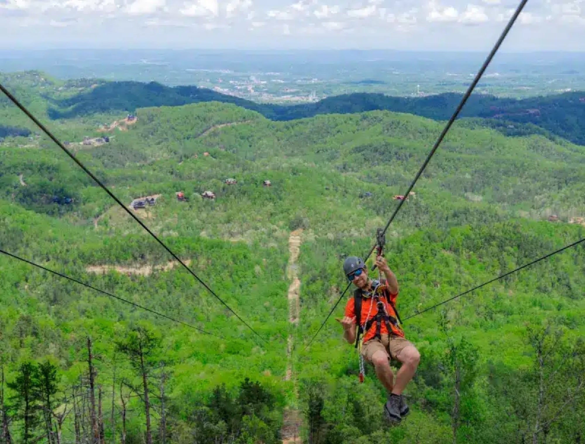 Ziplining over forested hills and distant town views.