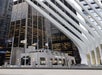 Modern cityscape featuring tall glass buildings with a Mercer Labs storefront at street level, surrounded by flags and intersecting architectural beams.