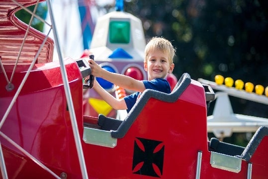 A young boy smiling while riding Airplanes and smiling at Michigan's Adventure in Grand Rapids, Michigan.