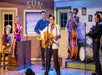 An Elvis impersonator singing and playing guitar center stage with other cast members behind him at the Million Dollar Quartet in Branson, Missouri.