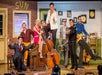 The cast of the Million Dollar Quartet posed around the piano with their instruments smiling.