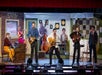 The cast of the Million Dollar Quartet on a 50s themed stage singing and playing various instruments.