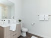 Modern bathroom with a wooden vanity, large mirror, toilet, and wall-mounted towel rack. White towels and toiletries are neatly arranged.