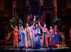A group of actors in colorful robes stands on stage with raised arms during a theatrical performance titled "Miracle of Christmas" at Sight & Sound Theatres.
