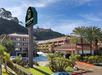 A hotel with beige buildings, a green sign reading "Mission View Inn & Suites", palm trees, and a hill in the background under a blue sky.