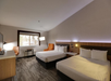 Two queen beds, bedside lamps, seating area, air condition, desk, and TV in a guest room.