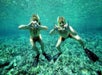 Two snorkelers posing underwater with hand signs.