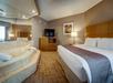 Hotel room with a large bed, a flat-screen TV on a wooden dresser, a lamp, wall art, and a corner jacuzzi.