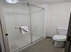 A bathroom with a glass-enclosed shower, a towel hanging on the shower door handle, and a white toilet next to it.