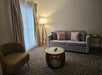 Living area with a sofa bed, ottoman, an armchair, and large windows.