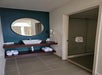 Bathroom vanity with a round mirror, fresh towels and toiletries.
