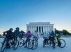 Group of people with bicycles in front of the Lincoln Memorial during sunset.
