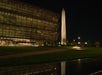 The Smithsonian National Museum of African American History and Culture is lit at night with the Washington Monument visible in the background.
