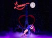 A couple dances under a starry sky with a neon "L'amour" sign and a moonlit Eiffel Tower backdrop.