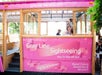 A pink Gray Line Sightseeing trolley promoting breast cancer awareness is parked with several passengers inside, including a child near the door.