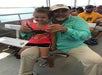 Channing with a young girl on his lap holding up a blue crab onboard the Explorer Saltwater Marsh.