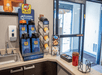 A coffee station with a four different dispensers and a small sink next to the glass entrance doors at My Place Hotel-Shakopee.