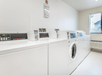 A laundry facility with a row of white washers and dryers at the My Place Hotel-Shakopee.