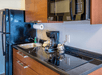 A kitchenette with a black fridge, small stove, sink, microwave, and coffee machine at the My Place Hotel-Shakopee.