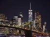 New York City skyline at night featuring the illuminated Brooklyn Bridge and skyscrapers with sparkling lights.