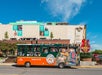 A Nashville tour bus parked on the street in front of the Hard Rock Cafe and a building with large country music banners.
