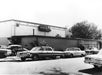 Black and white photo of parked cars in front of RCA Victor Studio building, with trees and a clear sky in the background.