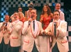 Ten cast members wearing red and white sing and dance