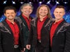 The members of New South Gospel wearing red shirts and black suit jackets standing together smiling.