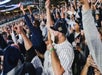 A crowd of Yankees fans screaming and cheering with their fits in the air at a Yankees game in NYC, New York.