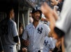 A Yankees player walking through a full dugout high-fiving other players and smiling.