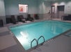 Indoor swimming pool with turquoise water, surrounded by lounge chairs and safety equipment. The pool area is well-lit with tiled floors and walls.